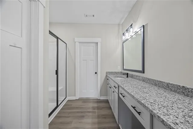 a bathroom with a granite countertop double vanity and a mirror