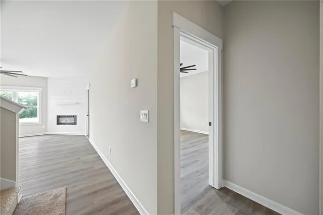 a view of a hallway with wooden floor and a bathroom