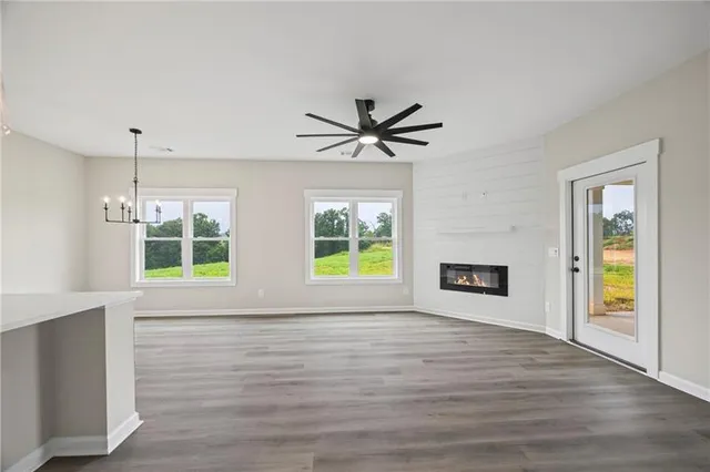 a view of an empty room with window wooden floor and a kitchen