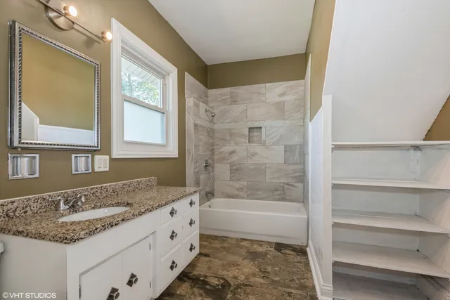 a bathroom with a granite countertop sink a mirror and a bathtub