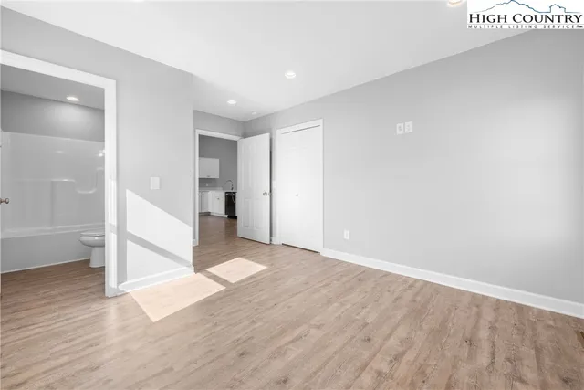 a view of a big room with wooden floor and a kitchen