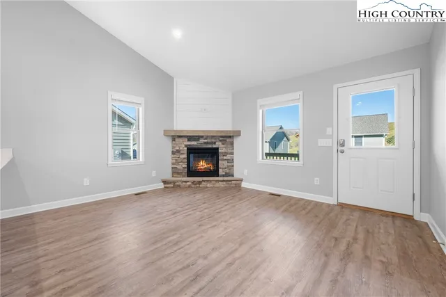 an empty room with wooden floor a fireplace and windows