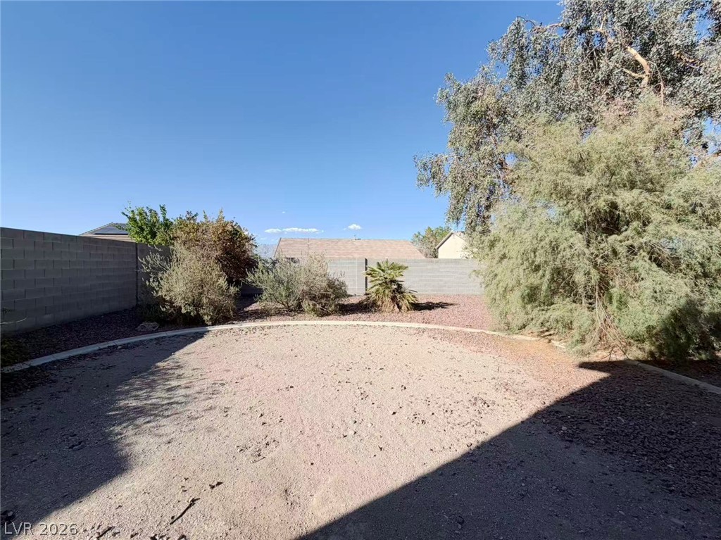 920 Hunters Ridge Way North Las Vegas, NV 89032 - Photo 15 of 16 Mature trees and block fencing enclose this low-maintenance desert backyard under clear blue skies.