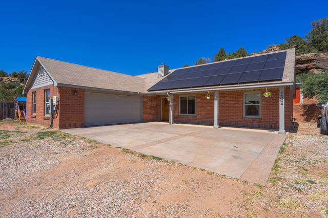 1504 Rome Way Apple Valley, UT 84737 - Photo 2 of 22 Brick exterior with a large front porch, solar panel array, two-car garage, and concrete driveway