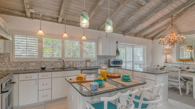 a kitchen with granite countertop a sink a stove a dining table and chairs