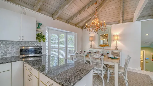 a kitchen with stainless steel appliances granite countertop a stove a sink dishwasher and white cabinets with wooden floor