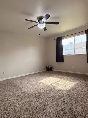 an empty room with windows and fan