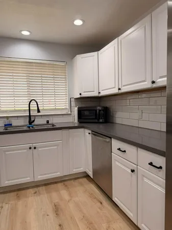 a kitchen with stainless steel appliances granite countertop white cabinets and window