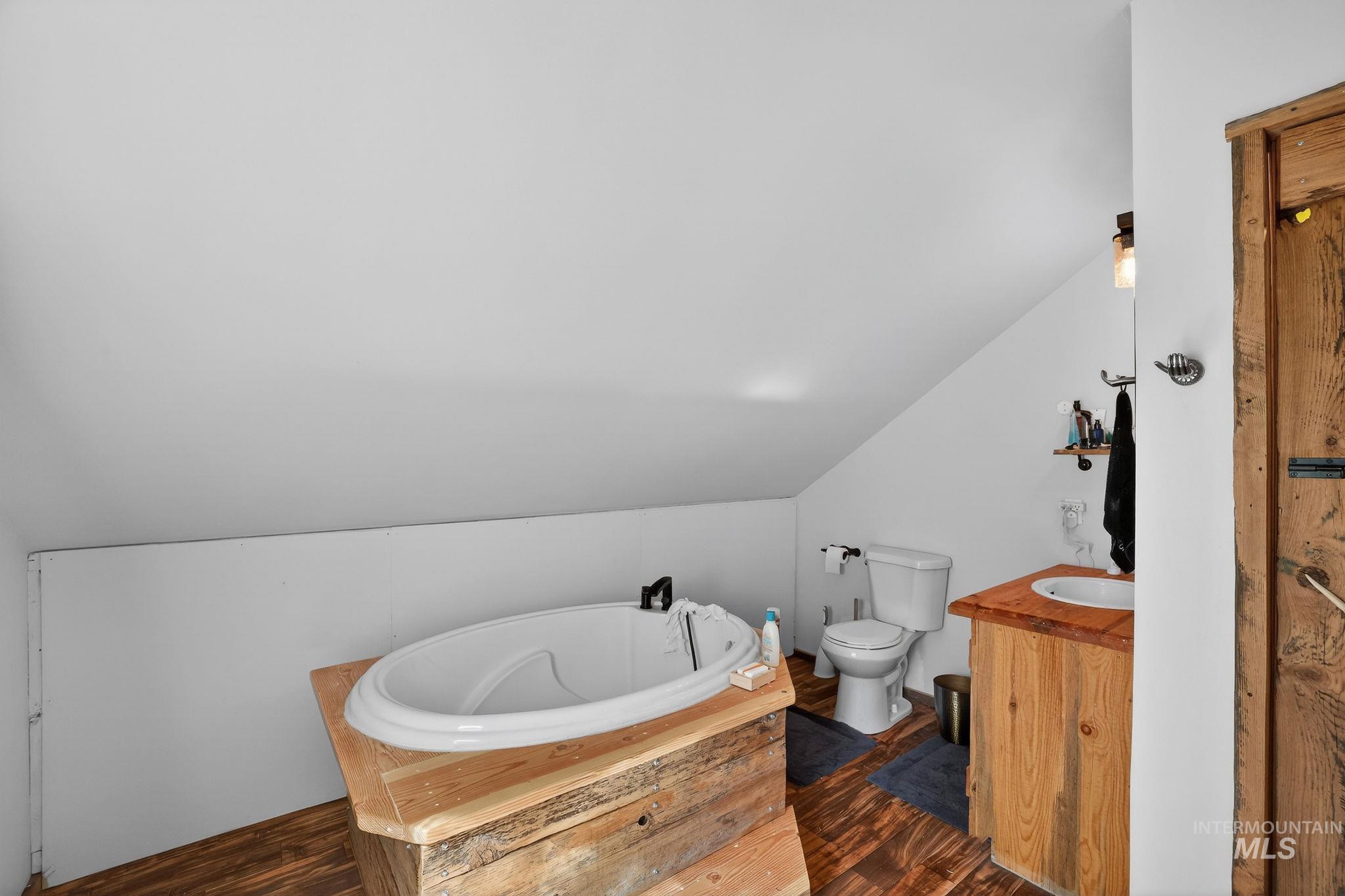 321 Secesh River Road McCall, ID 83638 - Photo 21 of 50 Bathroom featuring a standalone tub, wood-finish flooring, a wood vanity with an integrated sink, and a toilet