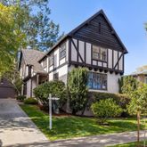 a view of a house with brick walls plants and large tree