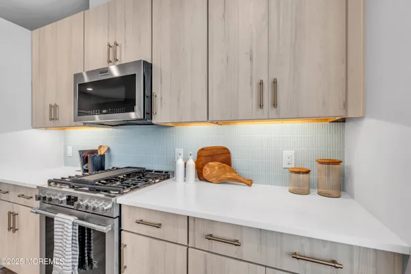 a view of living room with stainless steel appliances granite countertop a sink and a large window