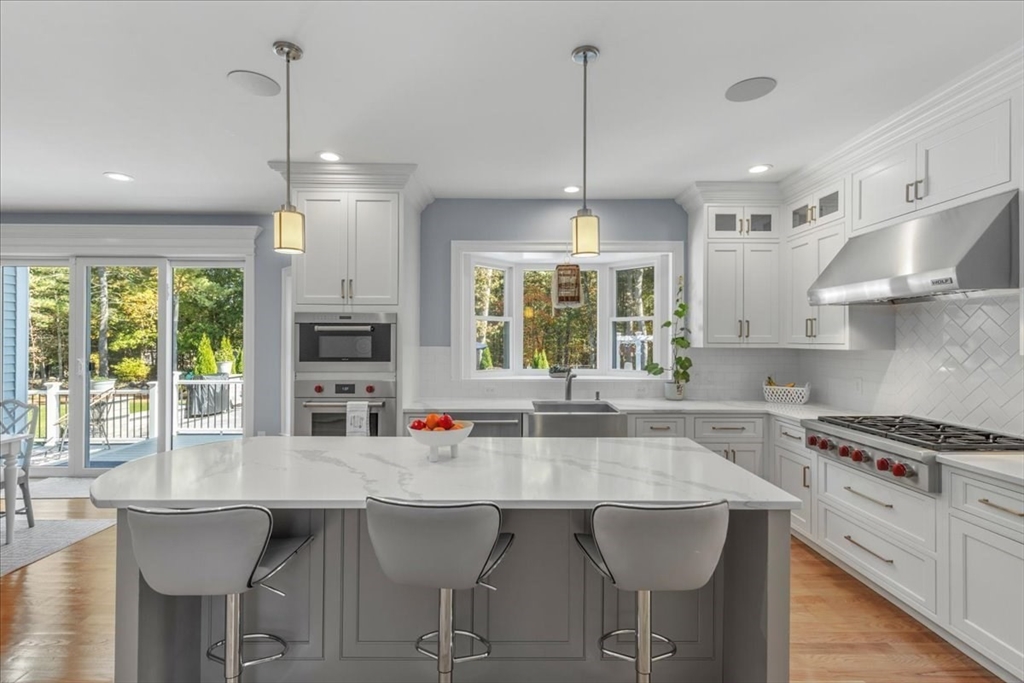 4 Lost Brook Trail Walpole, MA 02081 - Photo 7 of 42 a kitchen with stainless steel appliances granite countertop a stove a sink dishwasher a dining table and chairs with wooden floor