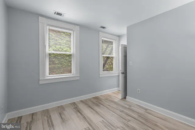 an empty room with wooden floor and windows