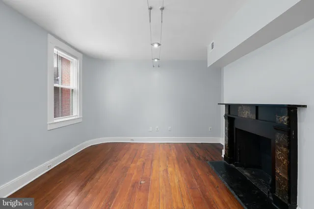 a view of empty room with wooden floor and fireplace
