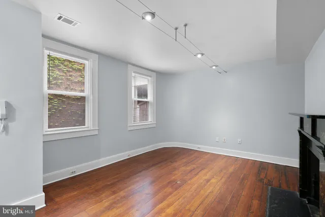 an empty room with wooden floor and windows