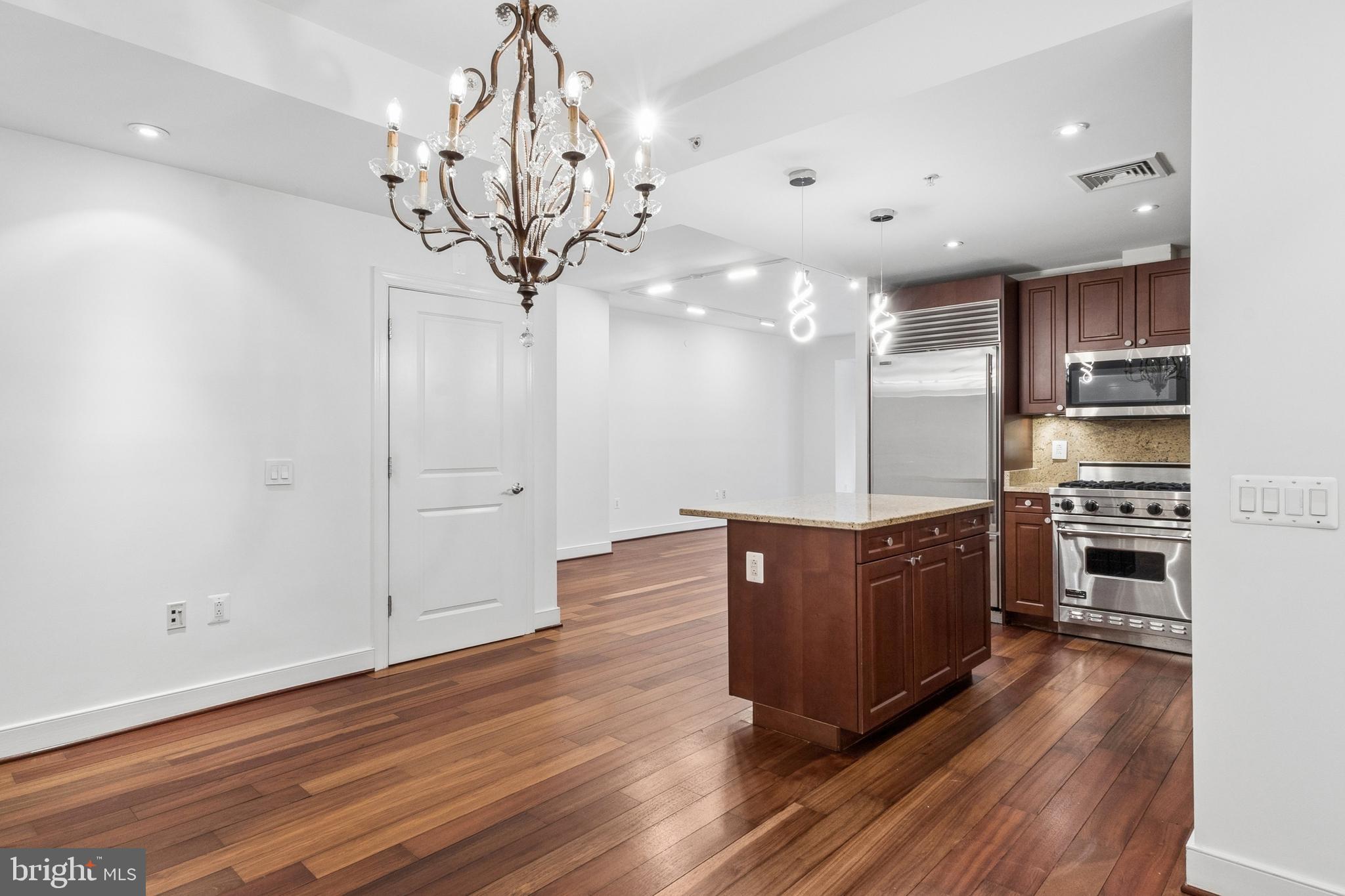 2425 L Street Northwest, Unit 431 Washington, DC 20037 - Photo 11 of 30 a large kitchen with stainless steel appliances a large counter top a stove and a chandelier