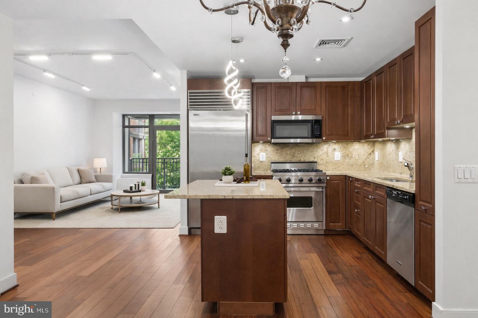 2425 L Street Northwest, Unit 431 Washington, DC 20037 - Photo 8 of 30 a kitchen with stainless steel appliances kitchen island granite countertop a stove top oven a sink a dining table and chairs with wooden floor