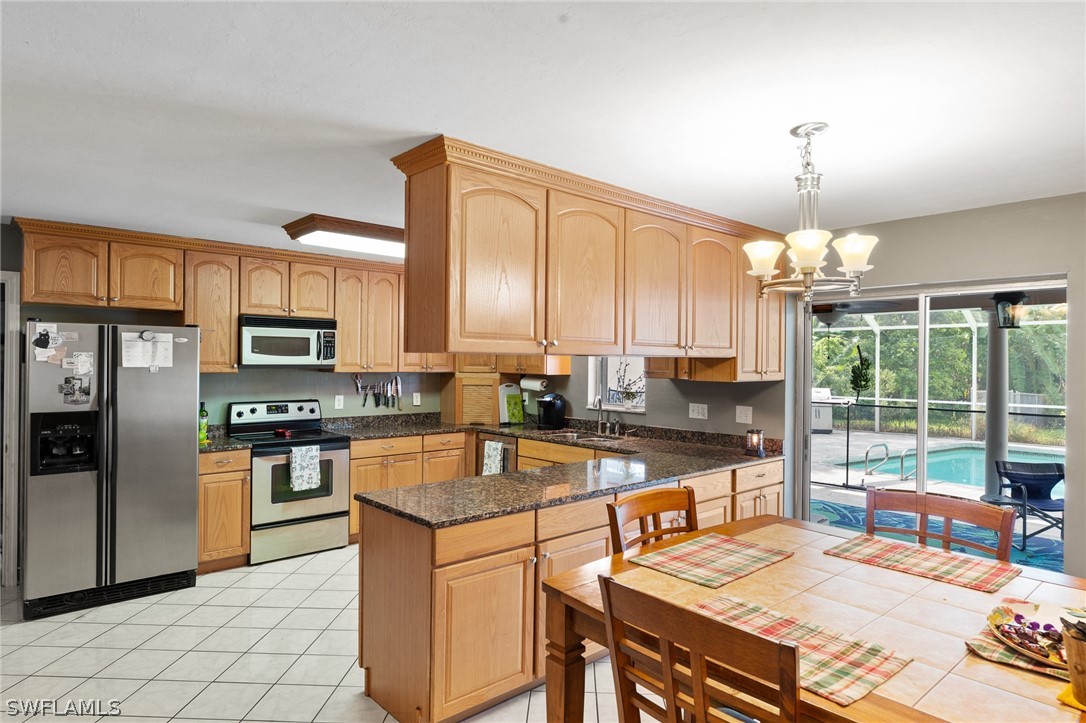 2340 Old N River Road LaBelle, FL 33935 - Photo 4 of 28 a kitchen with stainless steel appliances granite countertop a stove top oven a sink dishwasher a dining table and chairs with wooden floor