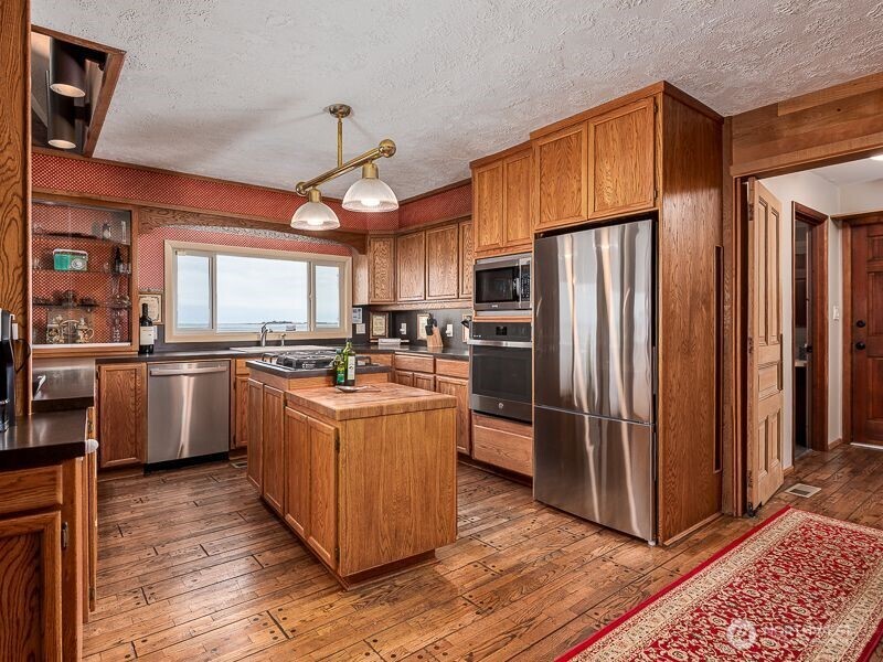 633 Highway 101 Chinook, WA 98614 - Photo 15 of 39 a kitchen with stainless steel appliances granite countertop a refrigerator a sink dishwasher a stove with wooden floor and cabinets