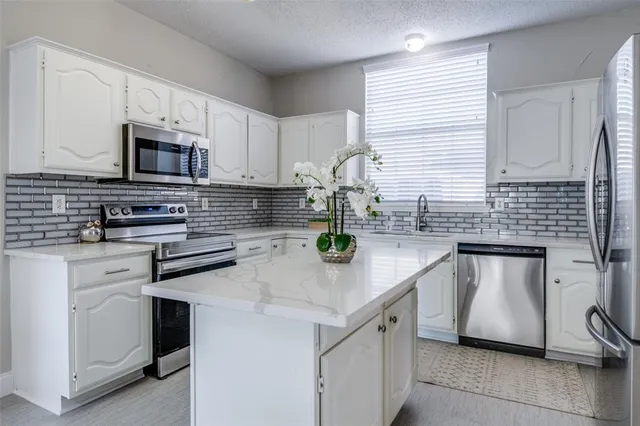 a kitchen with stainless steel appliances white cabinets a sink and a stove