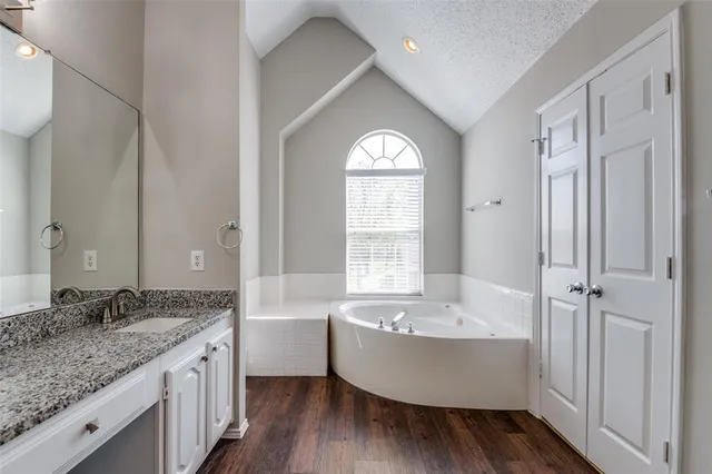 a bathroom with a granite countertop tub sink and mirror