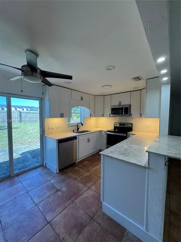 a large kitchen with stainless steel appliances granite countertop a sink and cabinets
