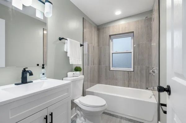 a bathroom with a sink a toilet a mirror a bathtub and shower