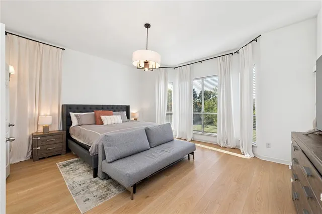 a spacious bedroom with a bed chandelier and a window