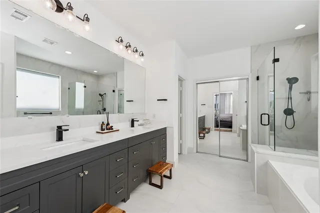 a en suite bathroom with a double vanity sink double mirror bathtub and shower