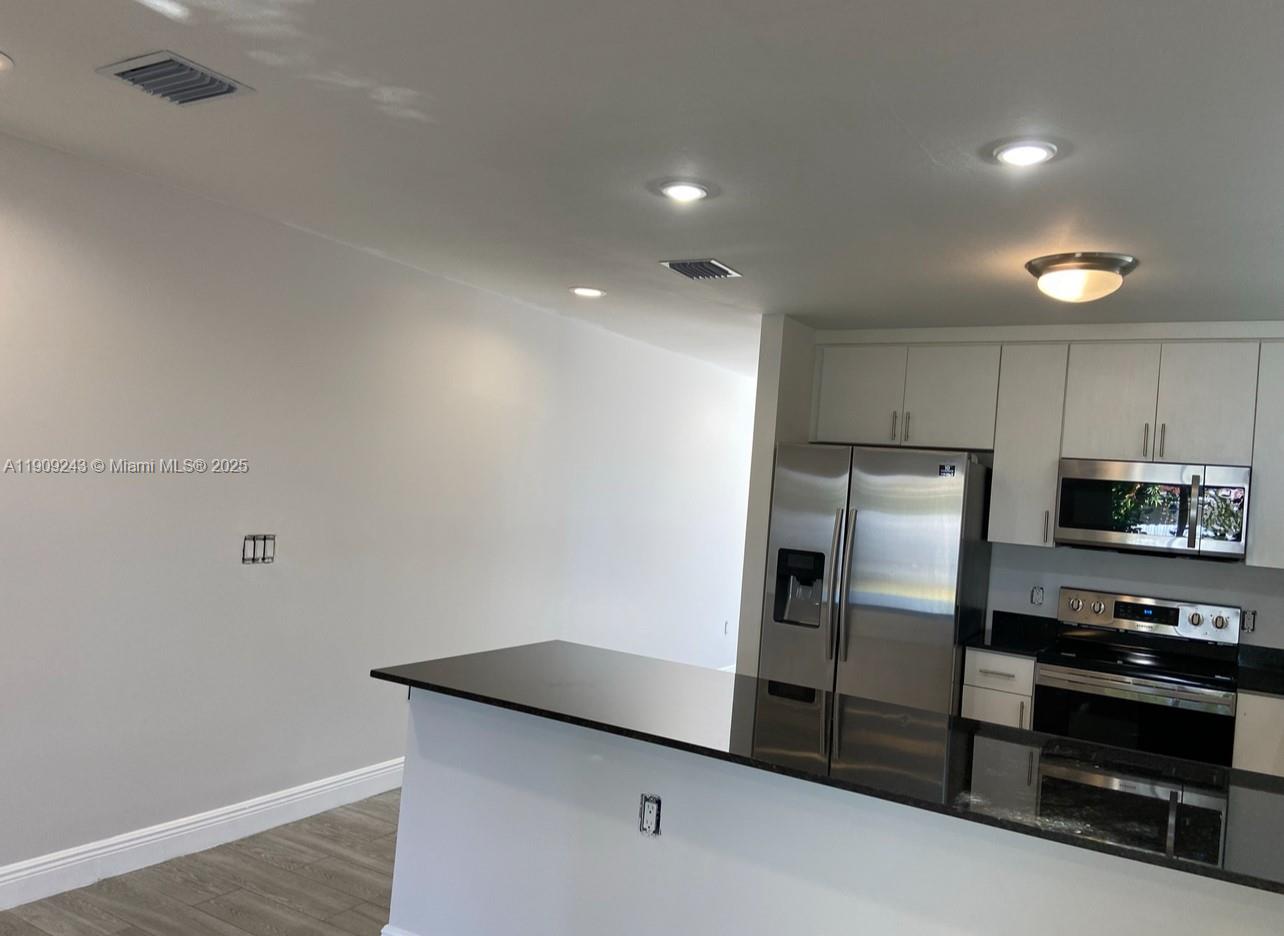 175 East 16th Street, Unit 175 Hialeah, FL 33010 - Photo 3 of 19 a kitchen with granite countertop a refrigerator and a stove top oven