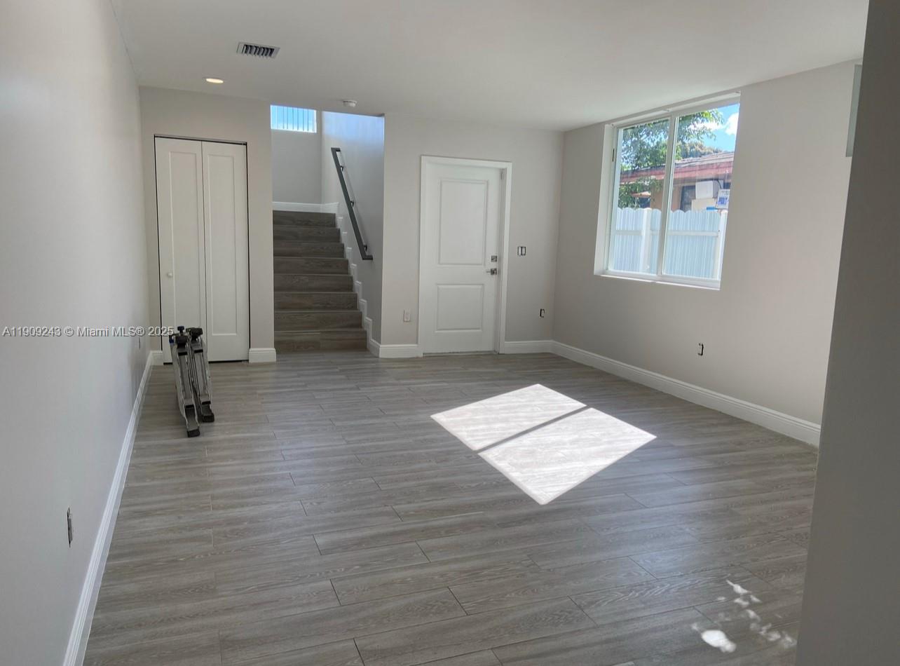 175 East 16th Street, Unit 175 Hialeah, FL 33010 - Photo 4 of 19 an empty room with wooden floor and windows