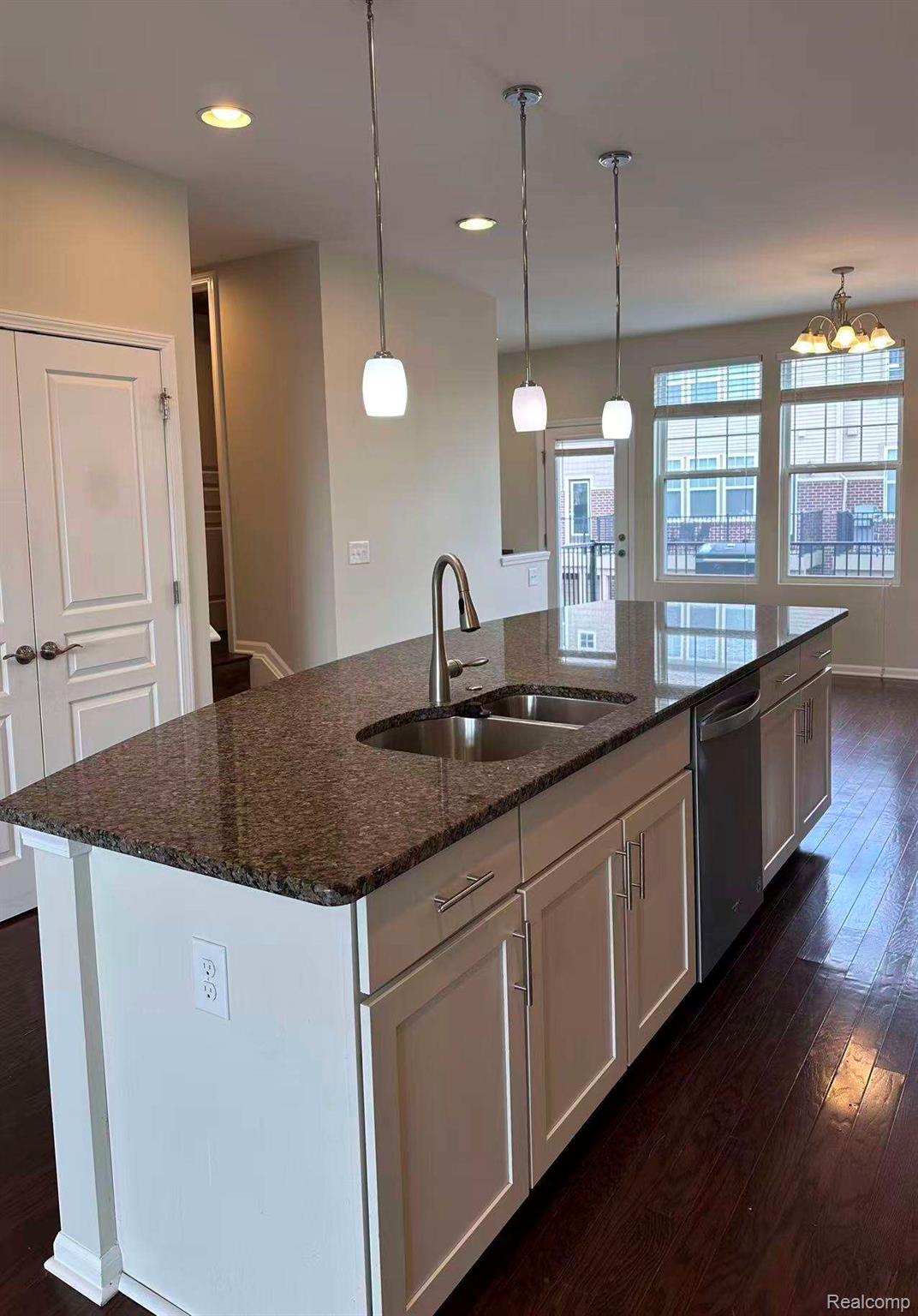 2578 Helmsdale Circle Rochester, MI 48307 - Photo 7 of 33 Kitchen island featuring granite-style countertop, stainless steel double-basin sink with a gooseneck faucet, white shaker-style cabinetry, and pendant lighting