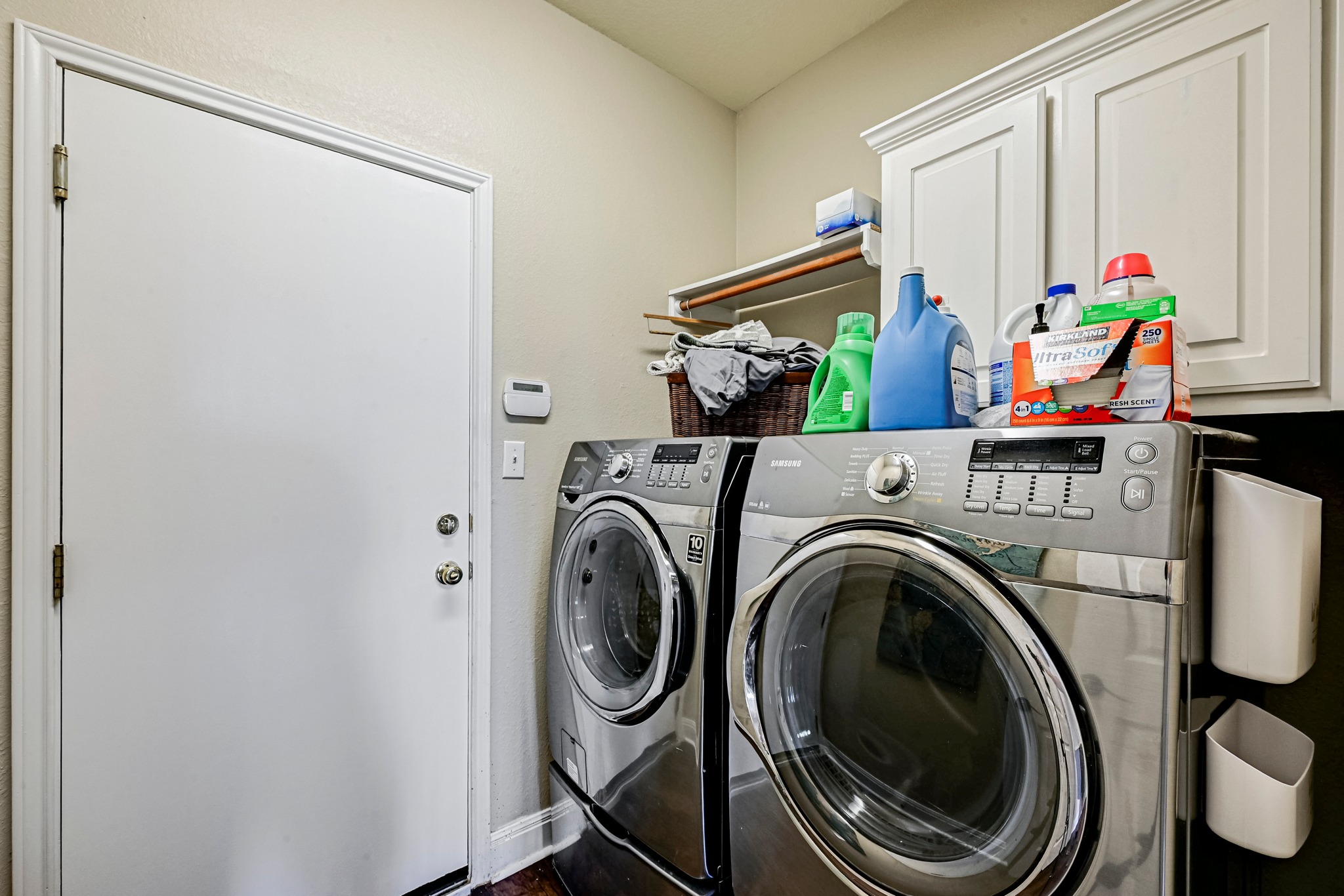 2408 Amen Corner Road Pflugerville, TX 78660 - Photo 23 of 40 Dedicated laundry area featuring wood-finish flooring, white cabinetry, and a wall-mounted shelf for storage