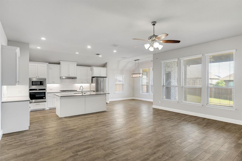915 Timber Ridge Drive Justin, TX 76247 - Photo 6 of 39 Open-concept living area featuring wood-finish flooring, a contemporary ceiling fan, and multiple windows with blinds
