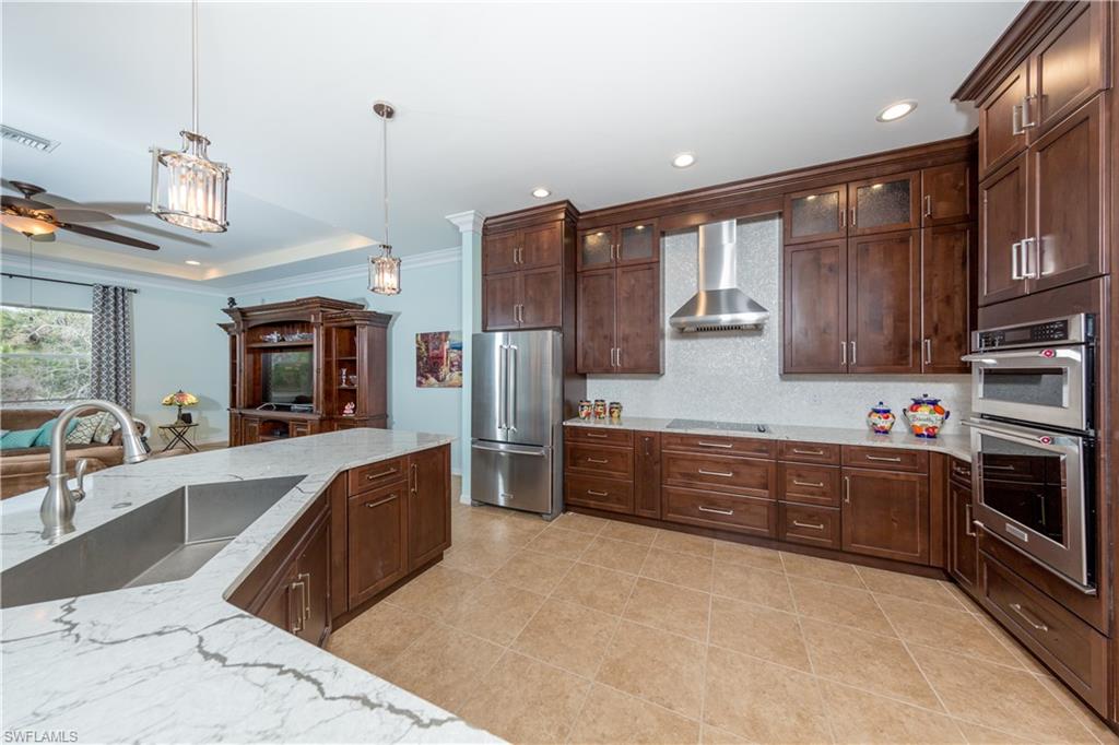 a large kitchen with stainless steel appliances wooden cabinets a stove and a sink