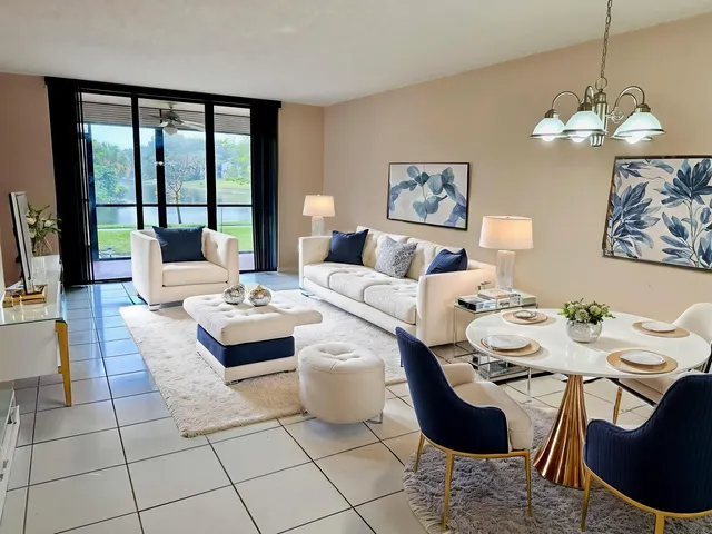 a living room with couches a table and chairs with kitchen view