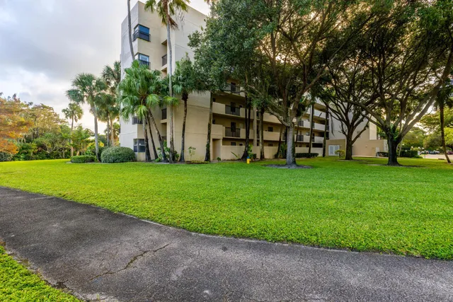 a view of a house with a yard and palm trees