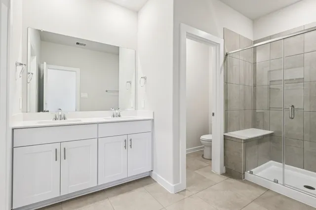 a bathroom with a double vanity sink toilet and shower