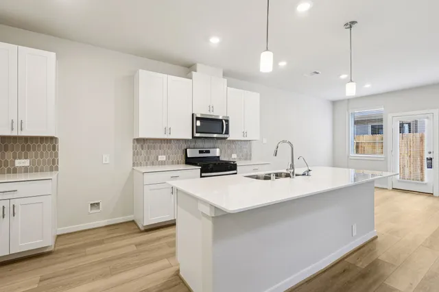 a kitchen with a sink a stove a microwave and wooden floor
