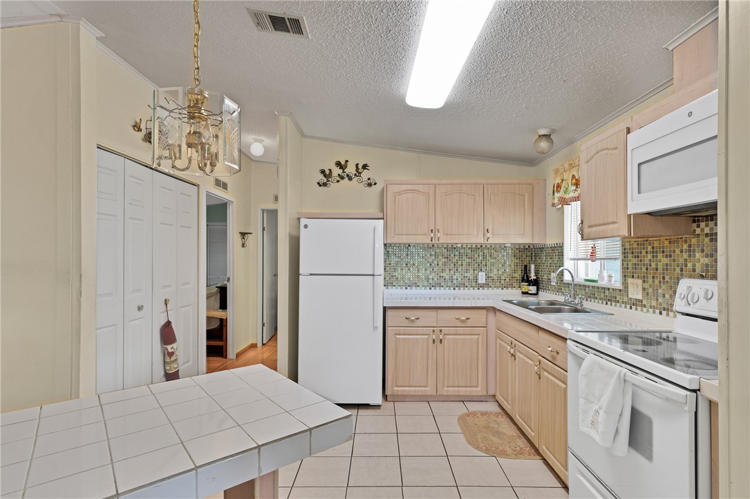 7571 Boxelder Road Micco, FL 32976 - Photo 9 of 36 a kitchen with white cabinets and white appliances