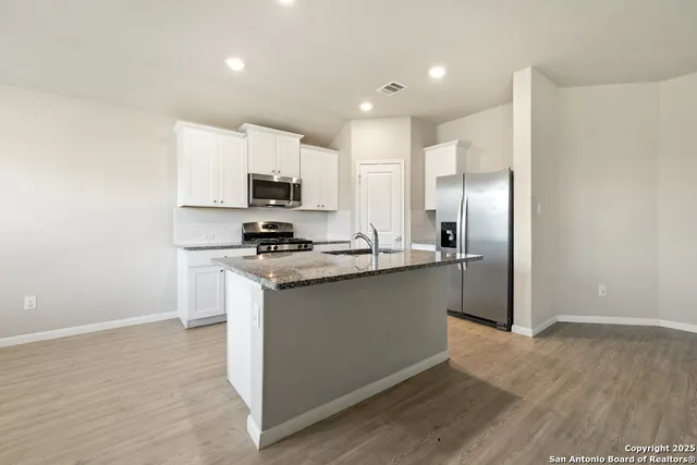 a kitchen with stainless steel appliances granite countertop a refrigerator stove top oven and sink