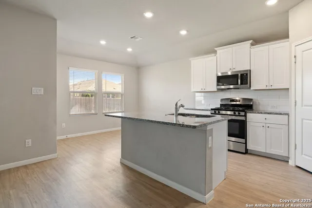 a kitchen with granite countertop a refrigerator and a stove top oven
