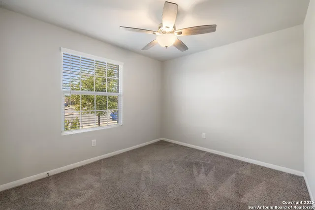 an empty room with a chandelier fan and windows