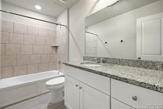 a bathroom with a granite countertop sink a toilet and bathtub