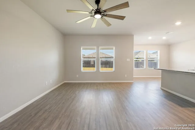 a view of an empty room with window and wooden floor