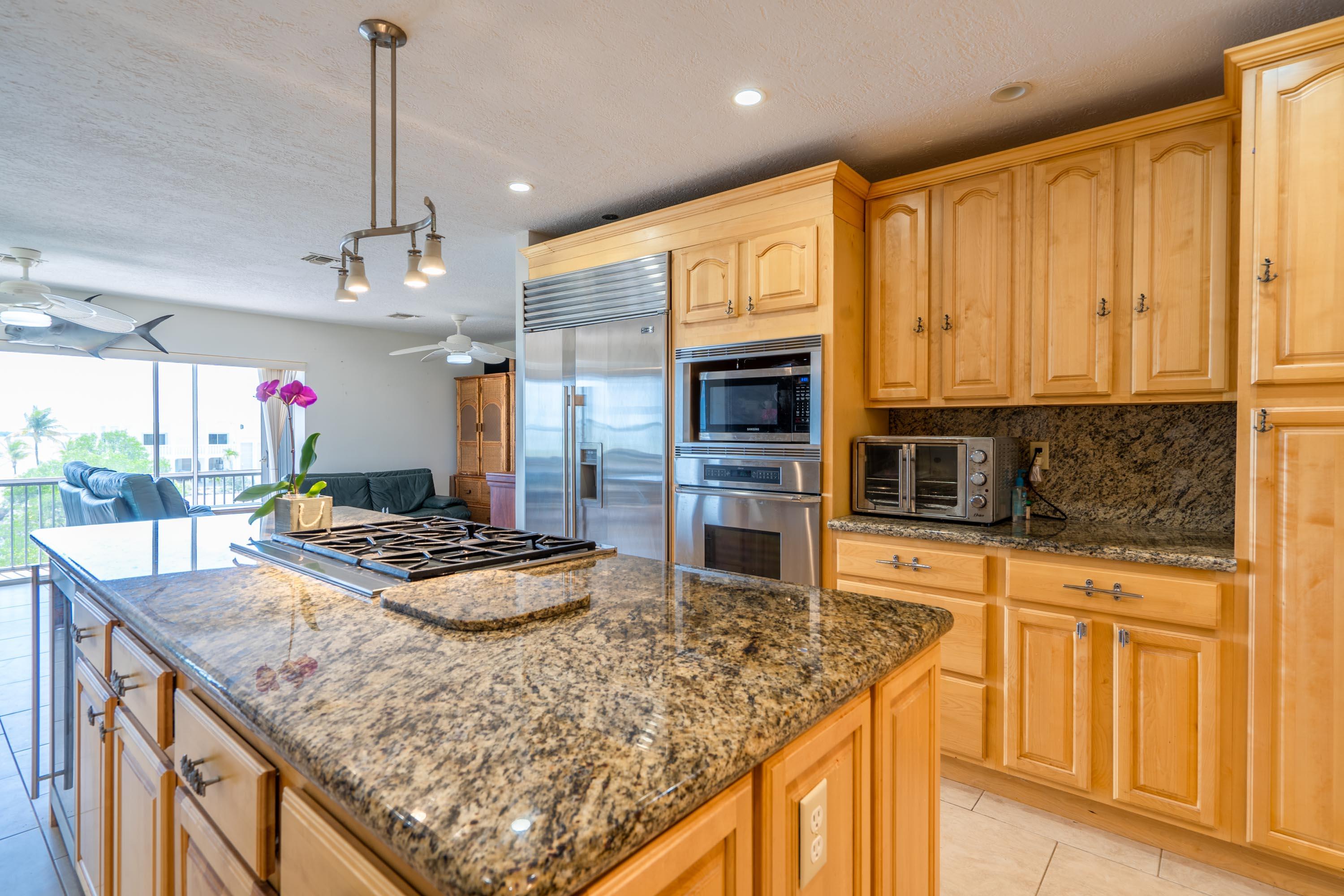 3814 Joyce Road Big Pine Key, FL 33043 - Photo 6 of 40 a kitchen with stainless steel appliances granite countertop a sink a stove and a wooden cabinets