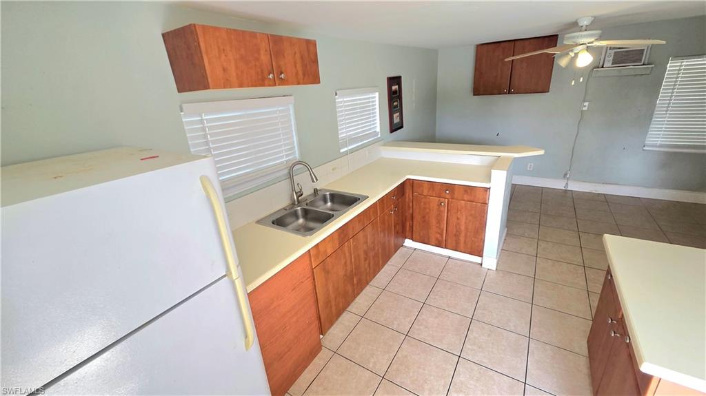 5529 Hardee Street Naples, FL 34113 - Photo 16 of 17 Guest House Kitchen area featuring a double basin sink, light-toned countertops, wood-finish cabinetry, and tiled flooring