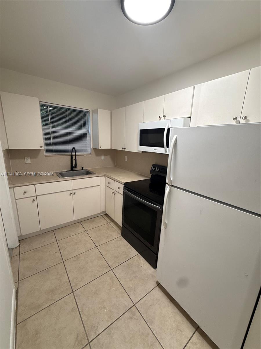 575 Northeast 82nd Street, Unit 10 Miami, FL 33138 - Photo 6 of 14 a kitchen with a sink a refrigerator and white cabinets
