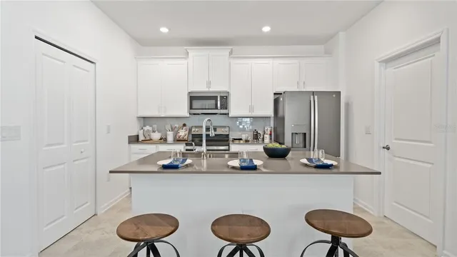 a kitchen with refrigerator and chairs