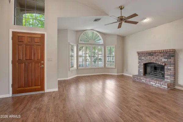 a view of an empty room with wooden floor and a window